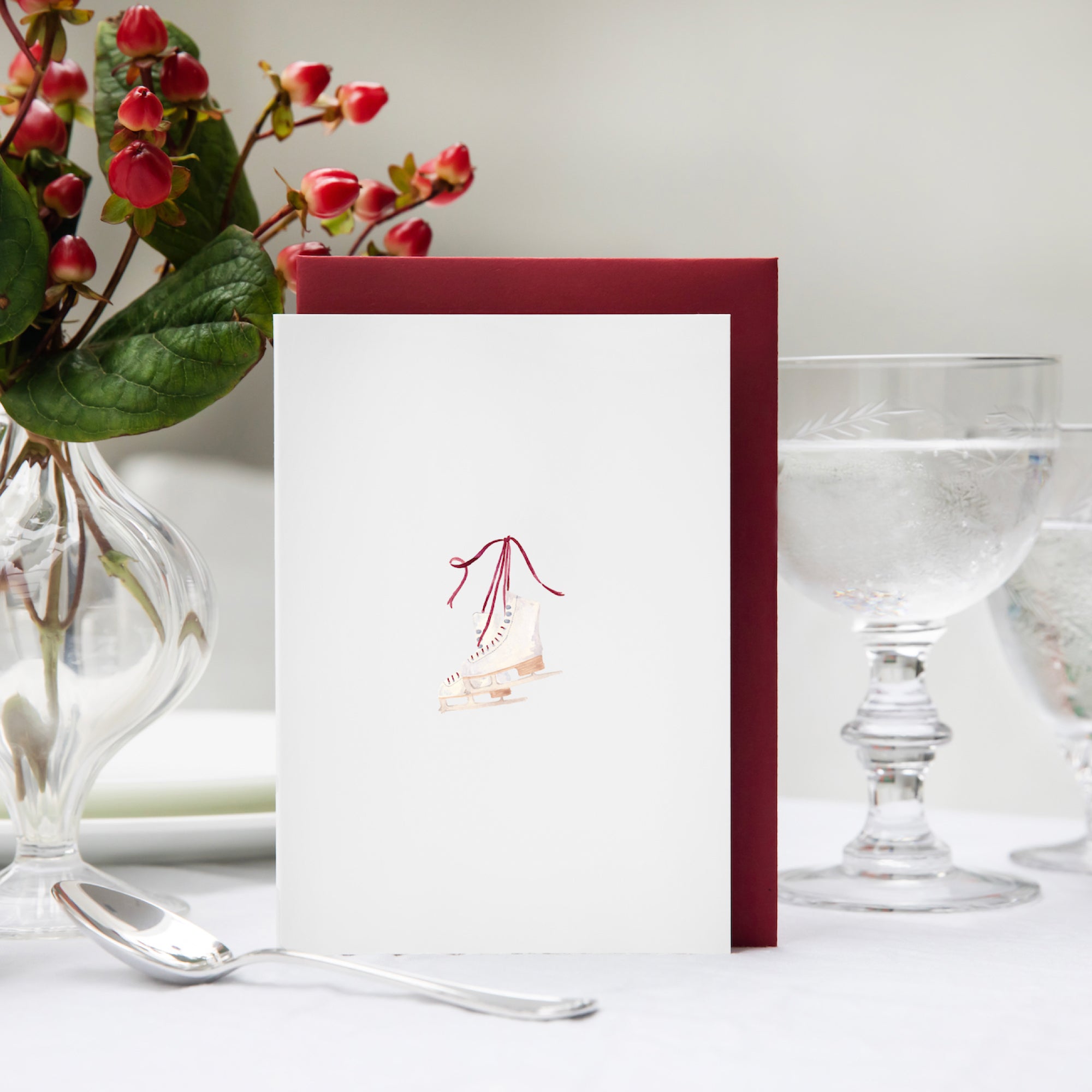 Luxury Christmas Card by Memo Press with a watercolour illustration of a pair of ice skates comes with a scarlet red envelope made in Britain

