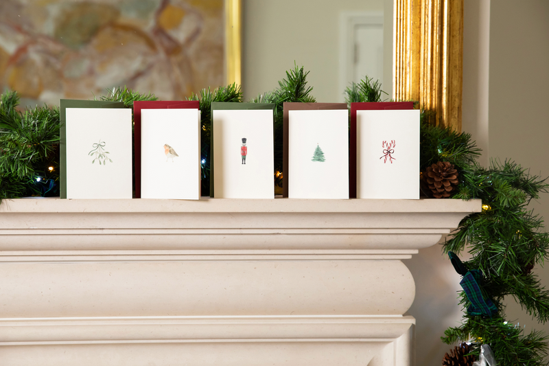 A set of five Christmas cards from Memo Press on a mantlepiece