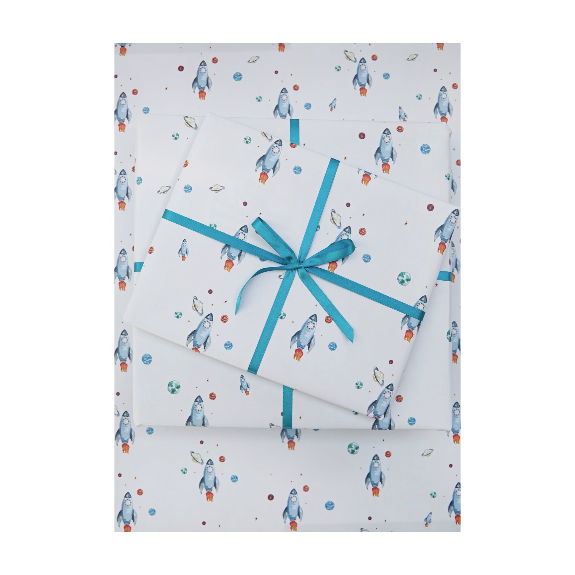 Wrapping paper with watercolour illustrations or rocket ships, planets and stars by Memo Press