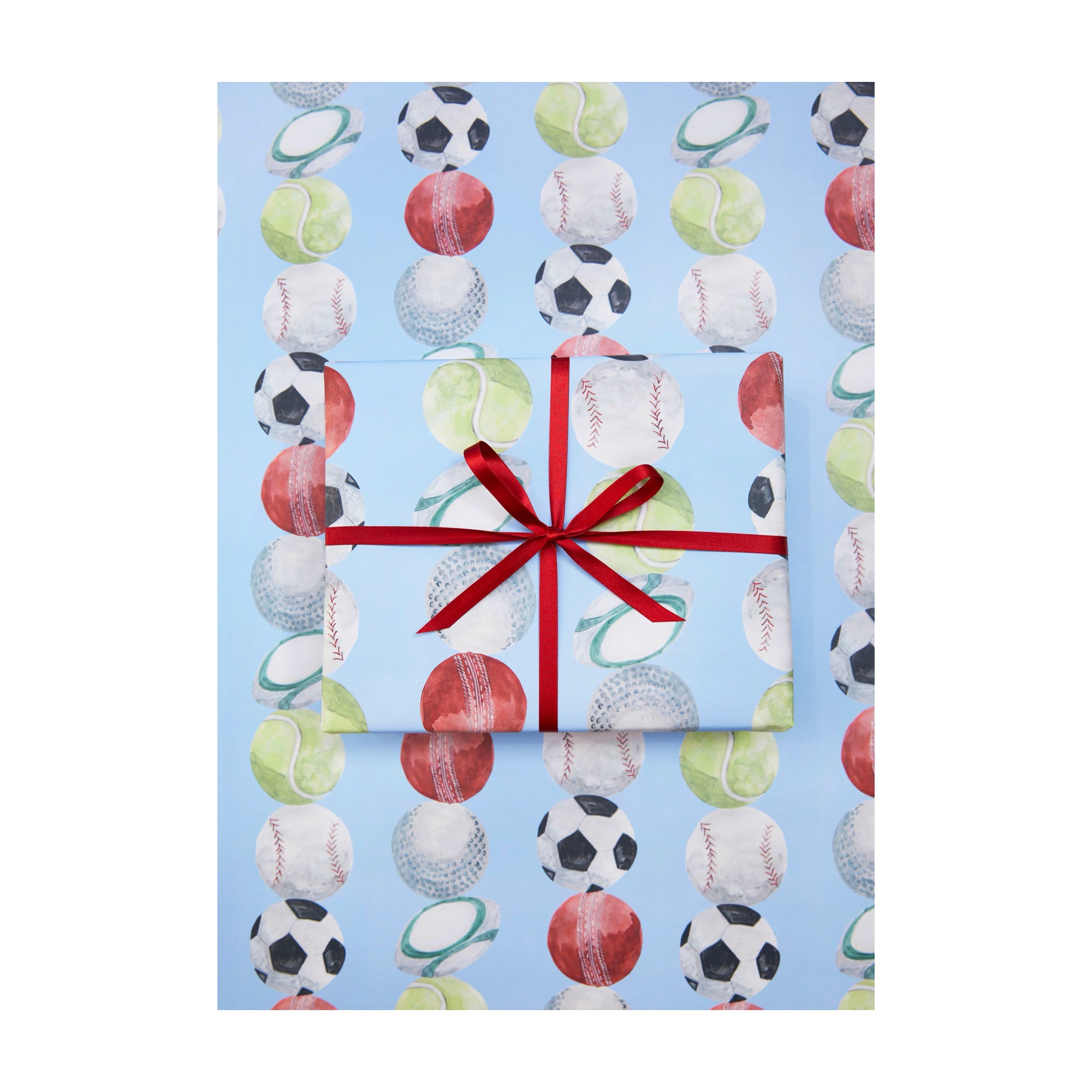 Wrapping paper with lots of kinds of sports balls illustrated on a blue background by Memo Press
